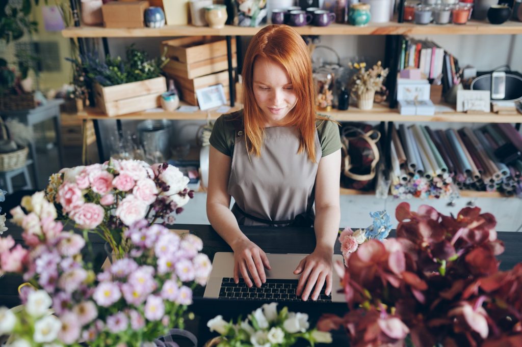 Pretty florist working with social media of flower shop