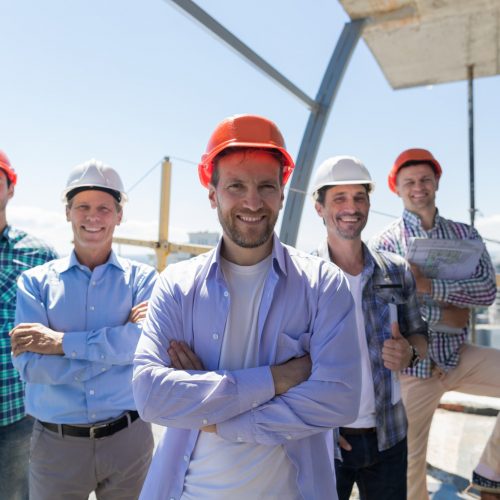 Builders Team Leader Over Group Of Apprentices At Construction Site, Happy Smiling Engineers